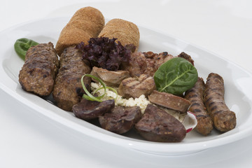 Traditional Romanian food plateau, with sausages, grilled meat, sweetbreads, potatoes, pickles, mustard, polenta, mushrooms, mici and vegetable salad, decorated with herbs, isolated on light backgroun