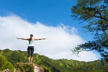 Fototapeta premium Woman standing up on a mountain feeling free with her arms in the air.
