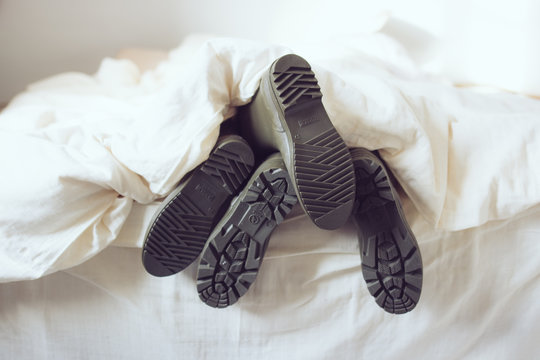 pieds homme femme avec des bottes sous la couette