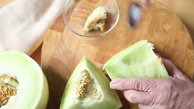 A man uses a spoon to scoop melon seeds 