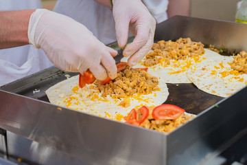 Close-up of hands of cook in gloves preparing fresh fajita. Healthy fresh tortillas with grilled chicken fillet, cheese. Concept of national food, healthy fast food
