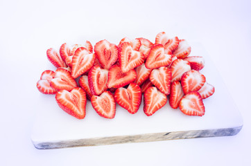 Close-up pile of fresh chopped strawberries on non-slip plastic cutting board isolated on white background. Heap, many of organic ripe sliced strawberry on chopping surface. Food concept. Vintage tone