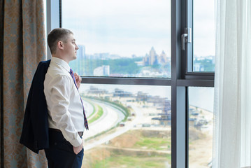 Fototapeta premium A young man standing at the window