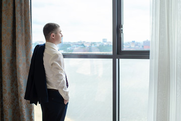 Fototapeta premium A young man standing at the window