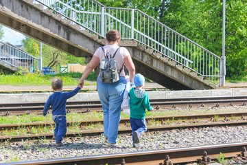 06.06.2017 Russia, Strugi-Krasnyye. A woman with two kids crossing the railroad across the tracks, over the tracks. Caution, danger, crossing in the wrong place..editorial