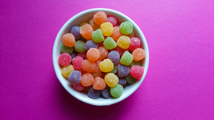 Sweet jujubes in white pot on pink background top view