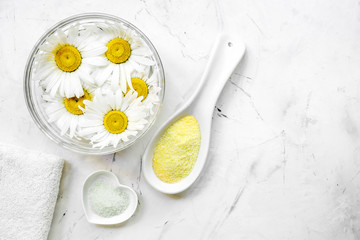 natural cosmetics with bowl of chamomiles for manicure on white textural background top view space for text