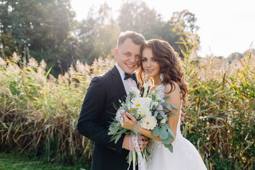 A nice, warm portrait of a stylish bridegroom and a charming bride in the nature