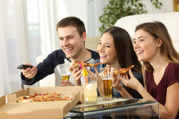 Friends watching tv and eating pizza