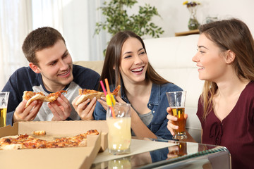 Friends talking and eating pizza at home