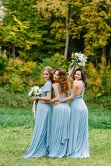 Beautiful cute girls are walking in the park. Three bridesmaids posing for a photographer....
