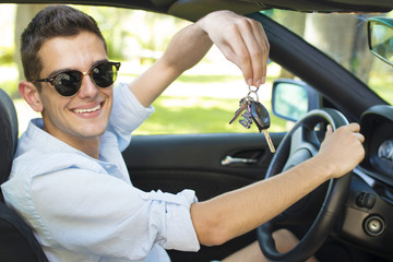 man with the keys to the car smiling behind the wheel