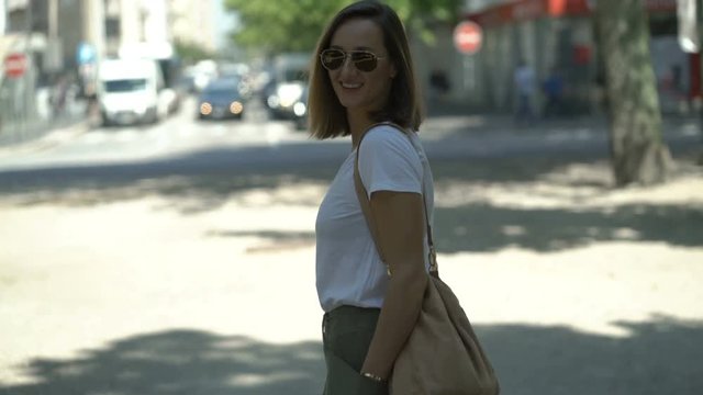 Portrait of happy, pretty woman standing near street in city 
