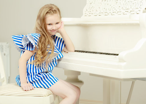 Adorable little blond girl in very short summer striped dress.