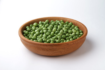 Raw peas in wooden bowl isolated on white background