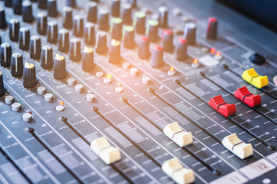 Slide the volume control of the audio mixer in a recording studio.