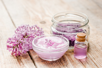 Fototapeta na wymiar spa cosmetic set with lilac flowers wooden desk background