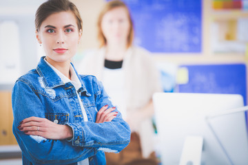 Two young woman sitting near desk with instruments, plan and laptop.