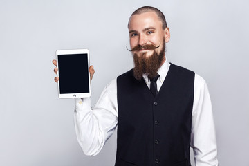 Handsome businessman with beard and handlebar mustache holding digital tablet and looking at camera...