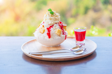 Kakigori strawberry cheesecake. Bingsu strawberry cheesecake from top-view..Bingsoo: white smoothie ice, cream, strawberry, Sweetened condensed milk mixed of Korean dessert in bowl on wood table