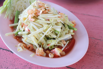 Raw mango salad in white dish.