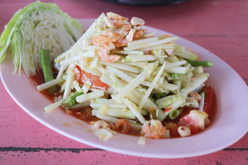 Raw mango salad in white dish.