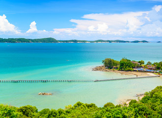 Fototapeta na wymiar The wooden bridge stretches into the sea, pier beach in Rayong, Thailand