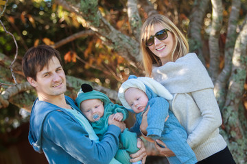 Naklejka premium outdoor portrait of young happy smiling mother and father with twin babies on natural background