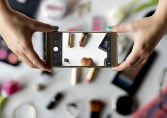 Fototapeta na wymiar Woman Hands Using Mobile Phone Capture Photo with Cosmetics Background