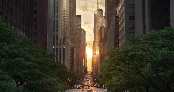 A cinematic wide evening establishing shot over 42nd Street in New York City during a "Manhattanhenge" sunset event.	 	