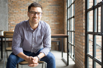 Positive Man Sitting at Window in Loft Office