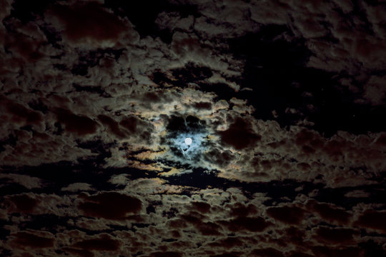 Moon in the night sky. Clouds and stars above them.