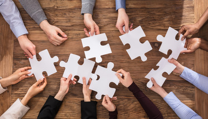 Businesspeople Hand Solving Jigsaw Puzzle