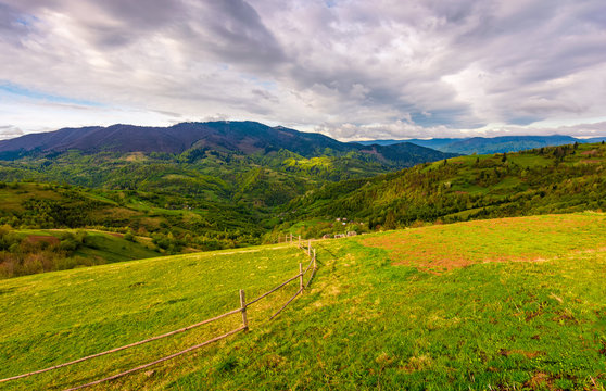 wooden fence through rural field on hillside