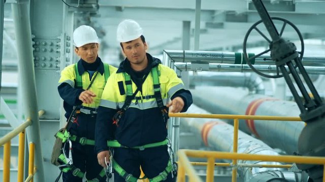 Engineers, in production plant as team discussing, industrial scene in background