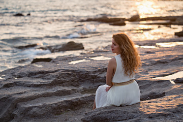 Fototapeta na wymiar Beautiful woman in white dress enjoying sunset