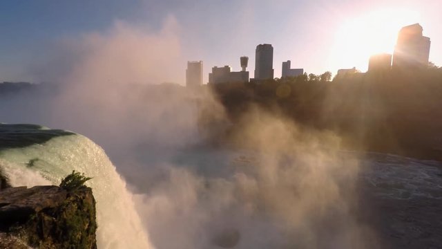 Roaring mist from Niagara Horseshoe Falls with skyline of Niagara Falls City, Canada.Tour boat Hornblower leaving the Falls at sunset. View from Niagara Falls State Park, New York, USA.Time lapse