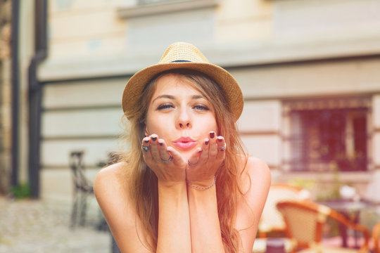 Young beautiful girl sending air kiss on the street.