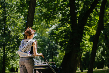 Young mother jogging with a baby buggy in summer park