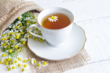 Chamomile tea on white wooden background
