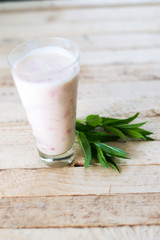 Milk shake yogurt with strawberry slices on a wooden background.