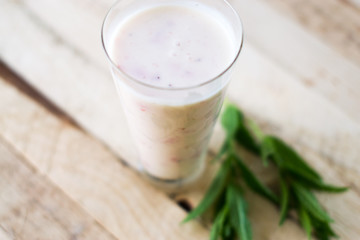 Milk shake yogurt with strawberry slices on a wooden background.