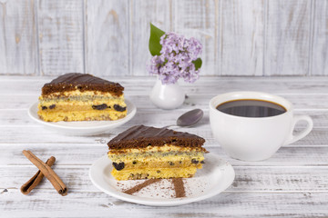 Chocolate piece of cake from biscuit dough with poppy seed, prune and walnuts and cup of coffee