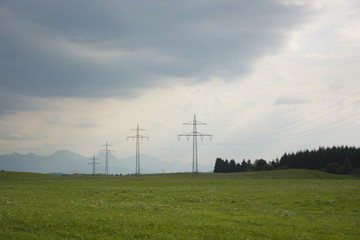 Fototapeta na wymiar Transmission Towers in a Field in Bavaria, Germany on a Cloudy Day