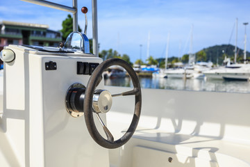 Black steering wheel on speed boat at pier