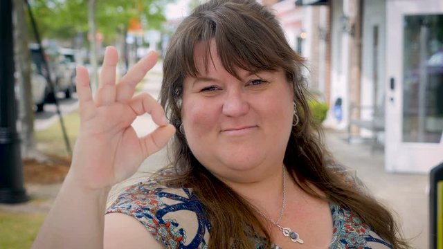 Happy smiling plus sized woman gives the a-ok outside