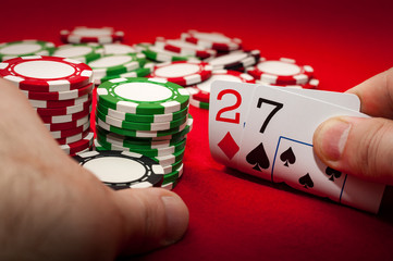 Bad poker gamble or unlucky hand concept with player going all in with 2 and 7 (two and seven)...