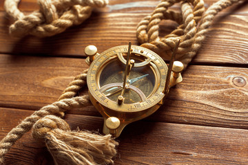 Compass and rope on wooden table. close up