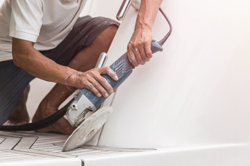 Yacht maintenance. A man polishing side of the white boat in the marina