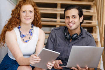 Portrait of two young people sitting at the stairs in office